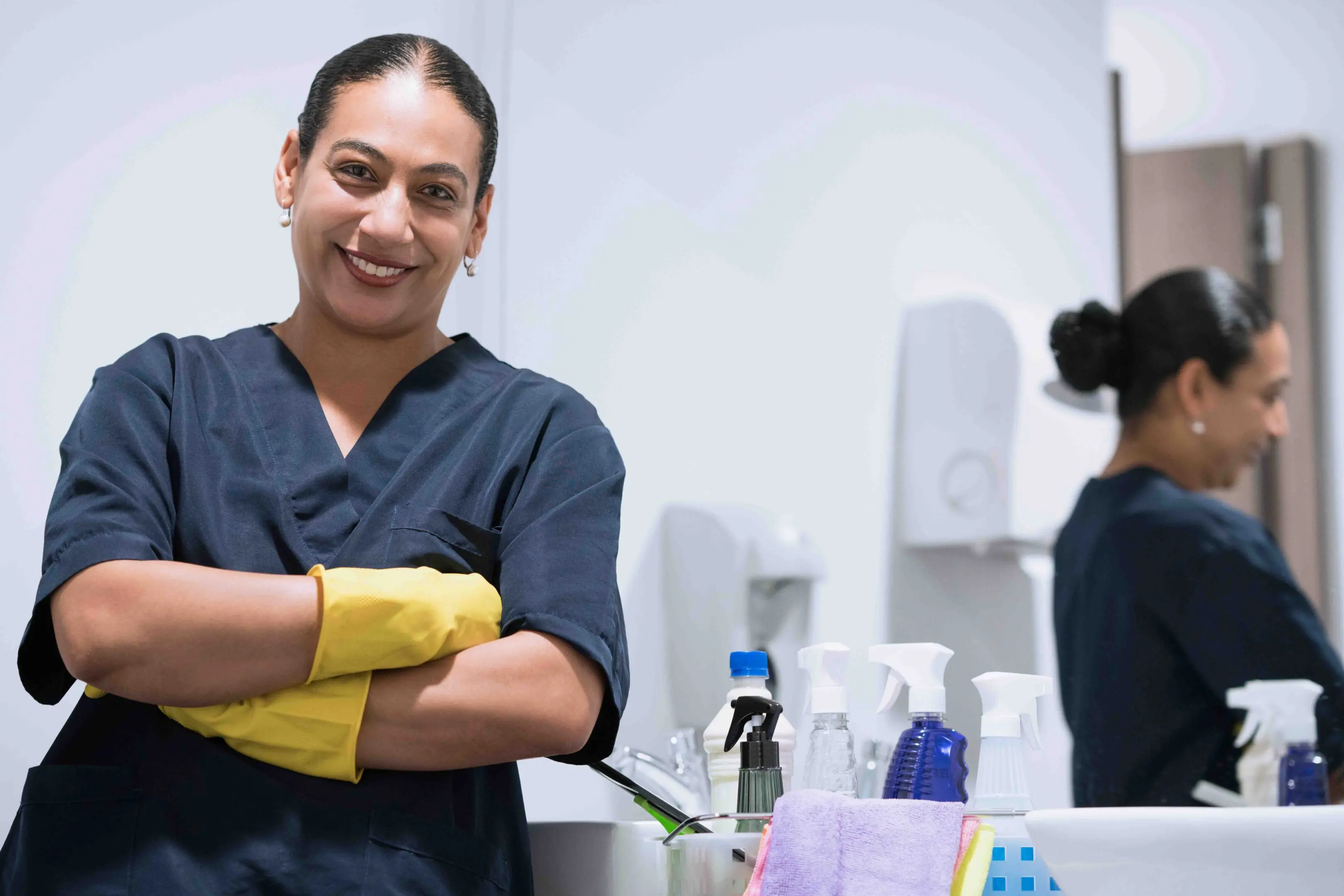 Latin woman between 35 - 45 years old is smiling cleaning the bathroom