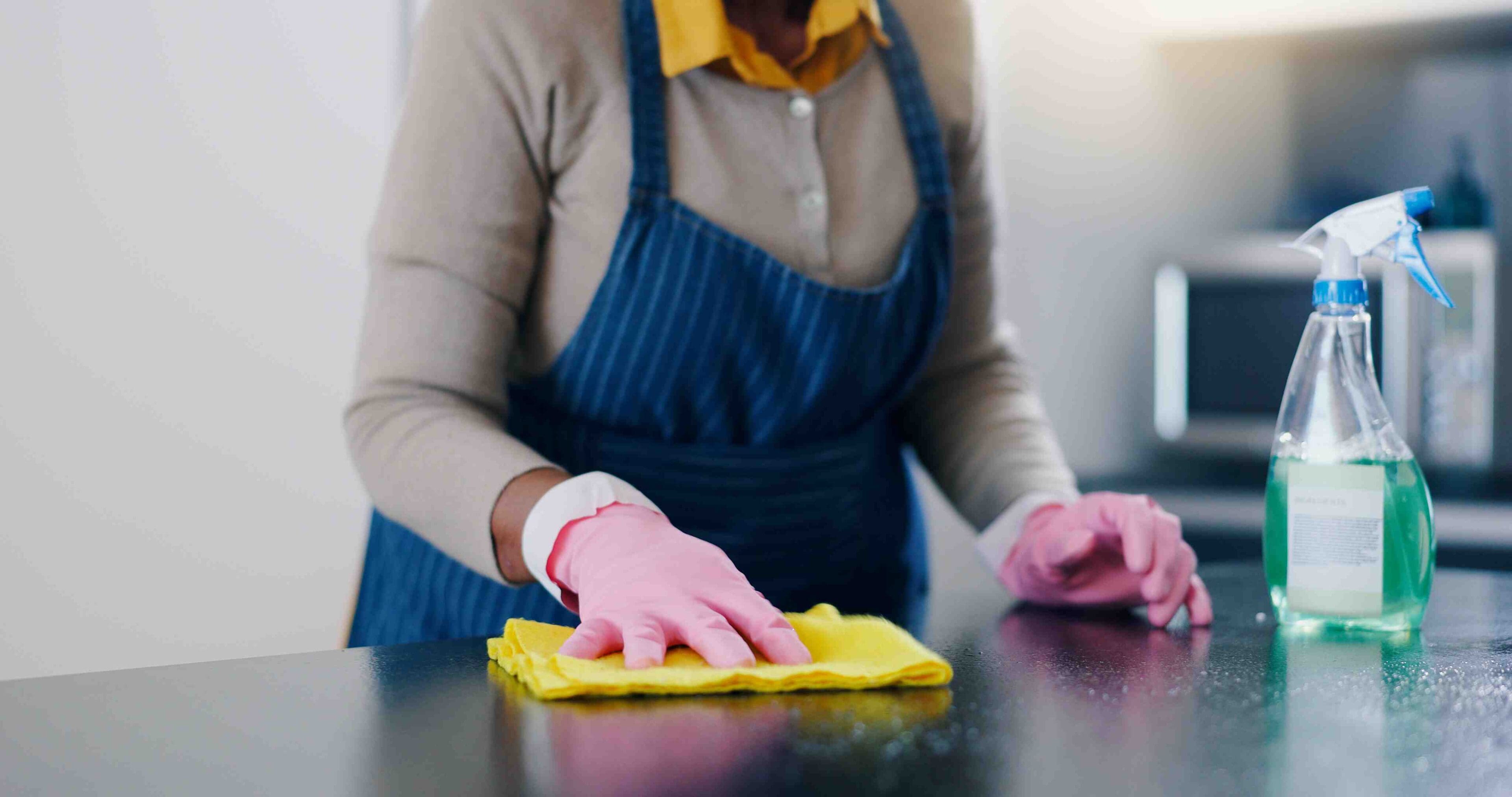 A person cleaning the counter top of a kitchen.