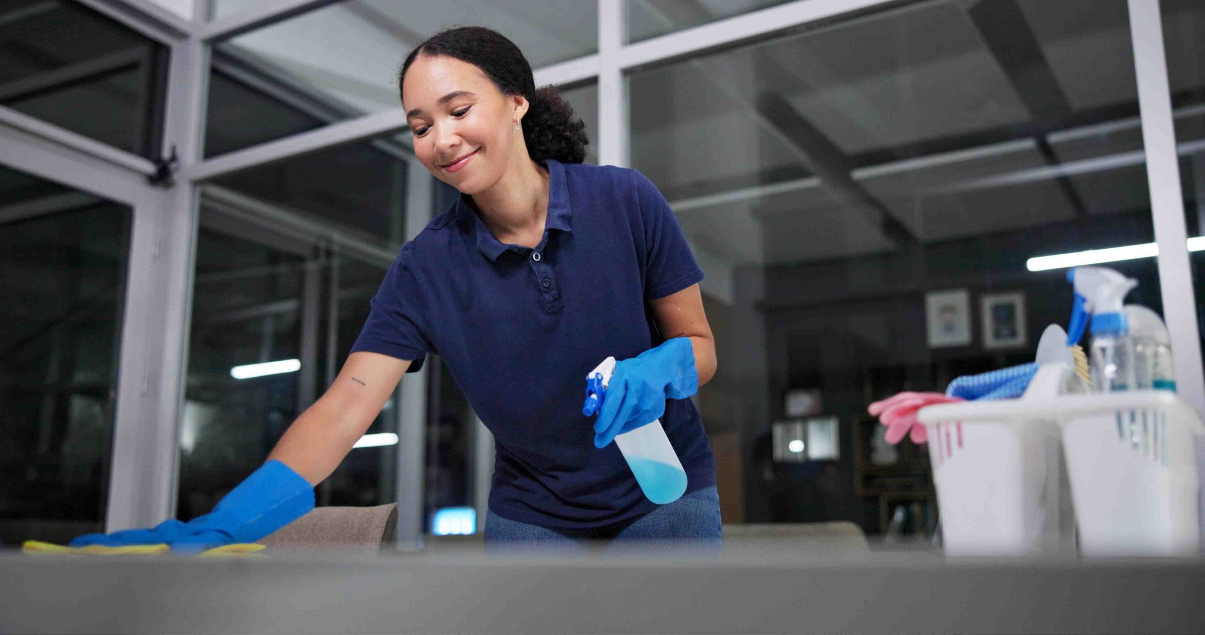 Cleaner, cleaning table woman in office for fumigation, spray disinfect and safety suit from disease risk in building. Maintenance, person and chemical liquid for pest control, health and hygiene